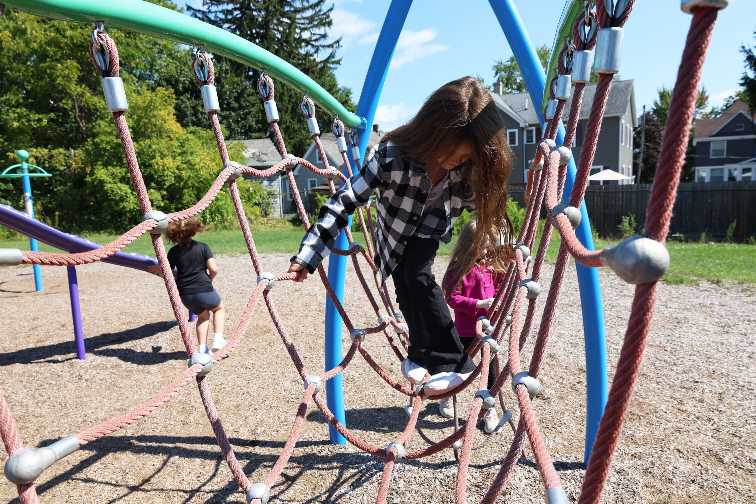 a girl with long dark hair plays on a playground outside