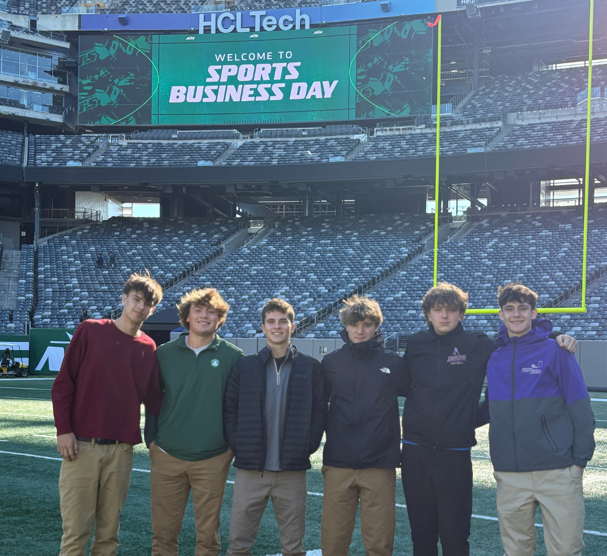male teen students pose on a professional turf football field