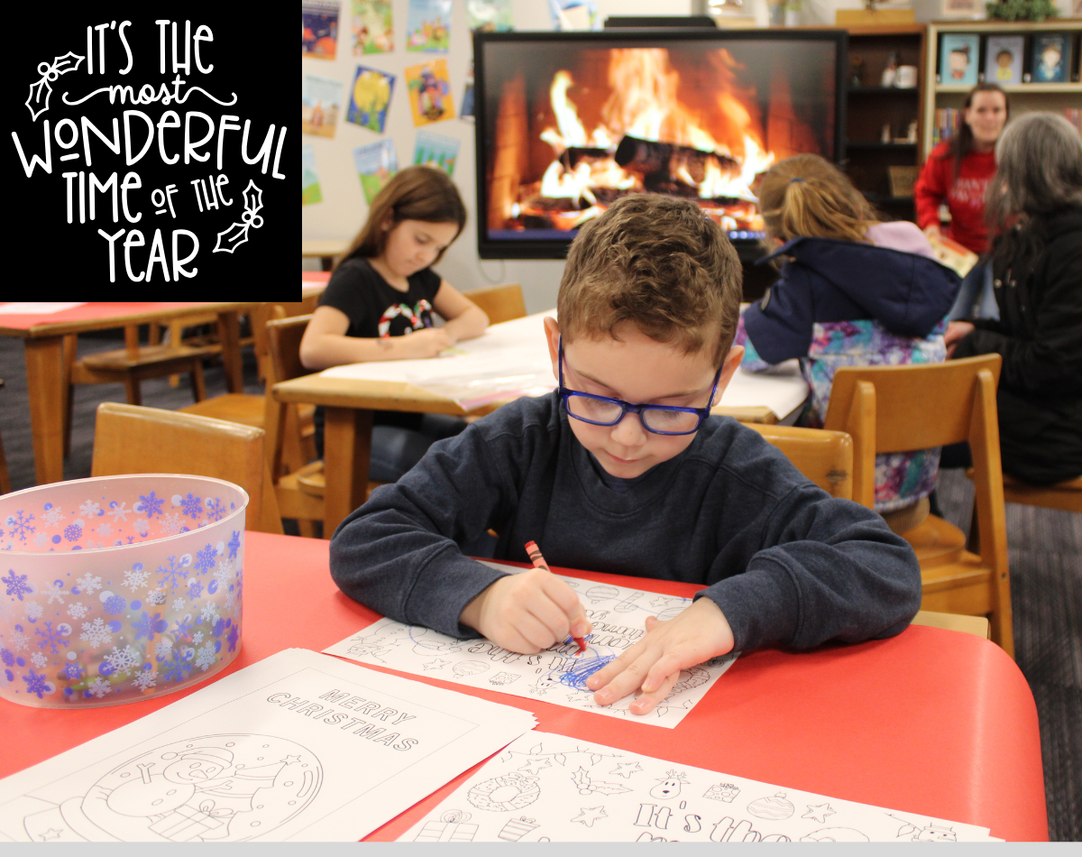 a young boy wearing glasses draws a picture in front of a fake fire airing on a TV screen
