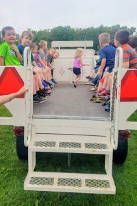 students sit in a wagon pulled by the tractor