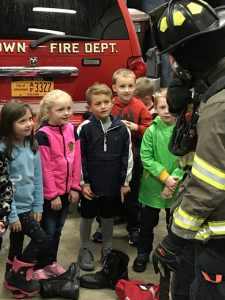 students stand in a group by a fire truck