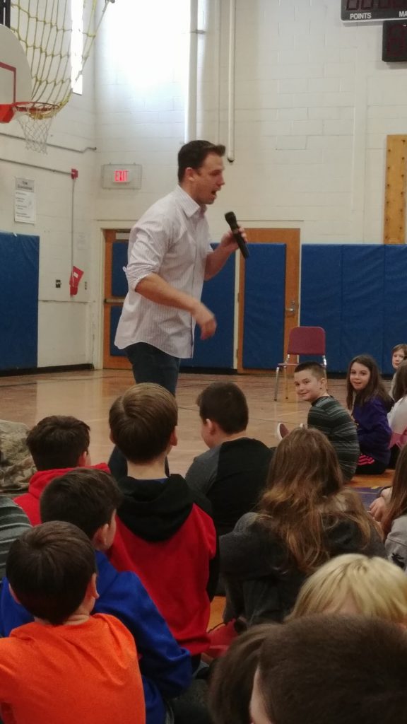 Poet Darrin Sardelli speaks to students in the gym