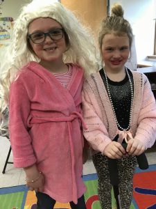 two students wearing wigs, lipstick, bathrobes, pearls