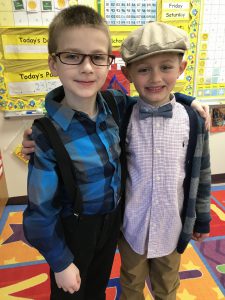 two students wearing glasses, caps, bow ties, suspenders