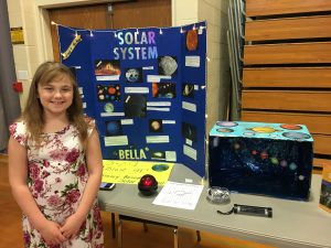 student next to her solar system display