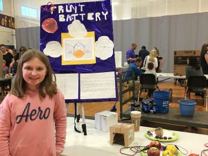 student next to a fruit battery display