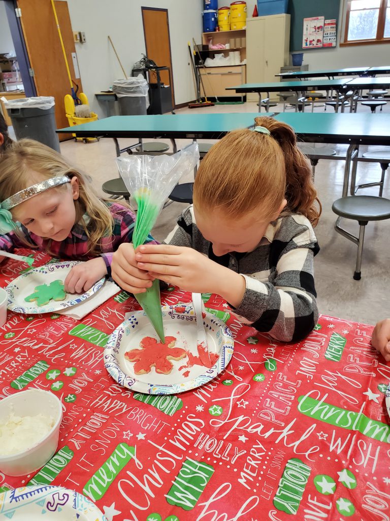 student using piping bag to decorate a cookie