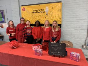 six students dressed in red selling lollipops
