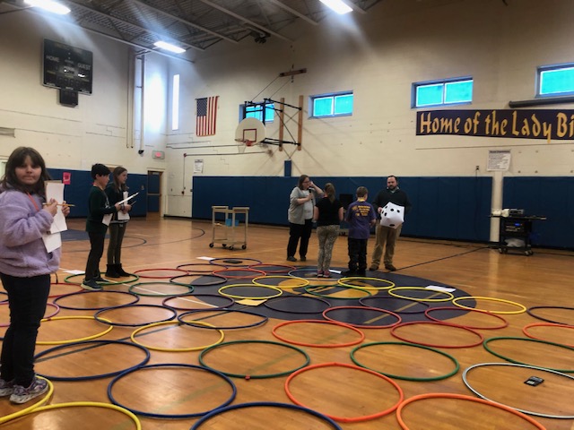 students stand in circles laid out on the gym floor