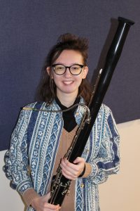 a young woman holds a bassoon