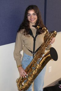 a young woman holds a baritone saxaphone