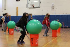 students participate in cardio drumming inside a gymnasium