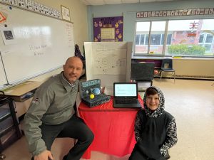 a teacher sits next to a student and his science project