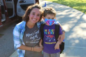 a mom leans down to pose with her son on his first day of school