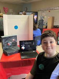 a student stands in front of his science project