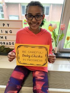 a girl holds up a sign that says "Be Careful, Baby Chicks in Progress."