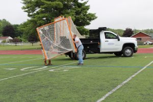 two men load a field hockey goal onto the back of a white work truck