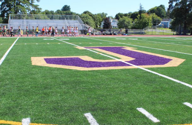 a turf field is shown with a purple and gold J