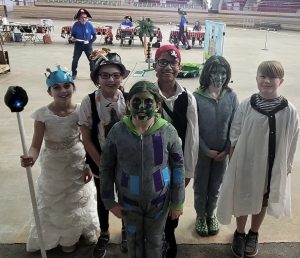 young students dressed in costumes pose in an arena