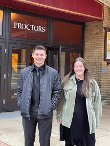 a teenaged boy and girl pose outside of a theater