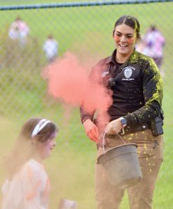 a woman throws a splash of color onto a child during a color run