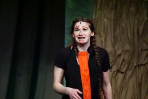 a young woman wearing black and red sings on a theatrical stage