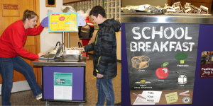 a student chooses a breakfast item from a cart in the hallway