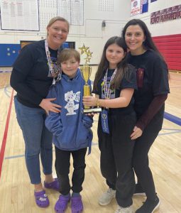 to adult females pose with two elementary students who are showing a trophy