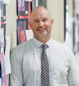 a man poses in the hallway of a school
