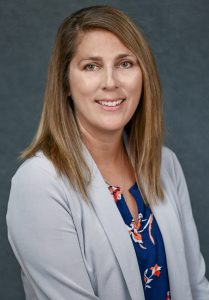 a woman wearing a grey jacket poses for the camera