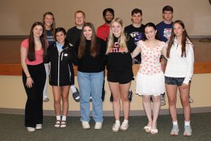 young teen students pose on a stage in an auditorium