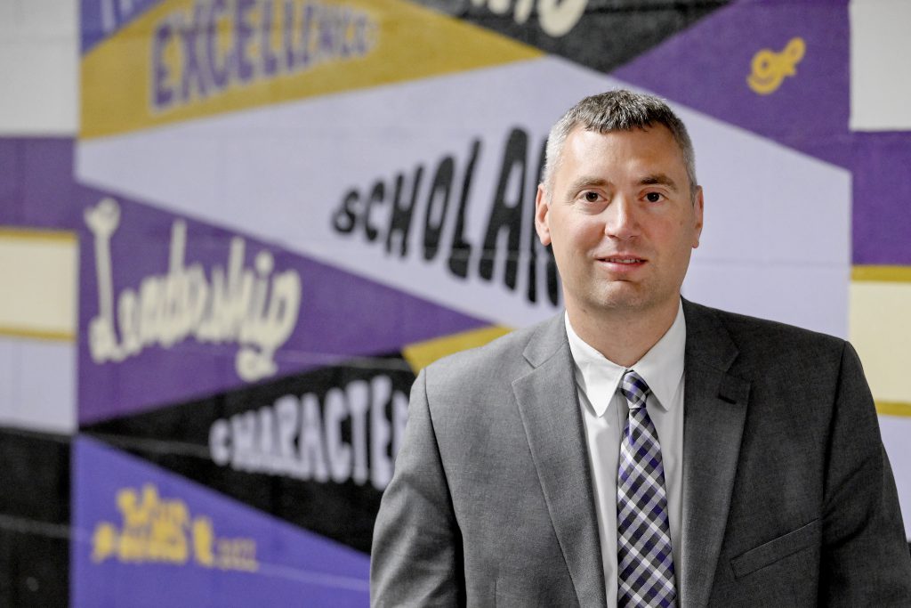 a man stands in front of a mural in a school hallway