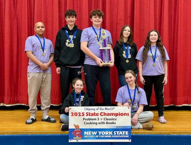 students wearing medals around their necks pose on a stage in front of a red curtain