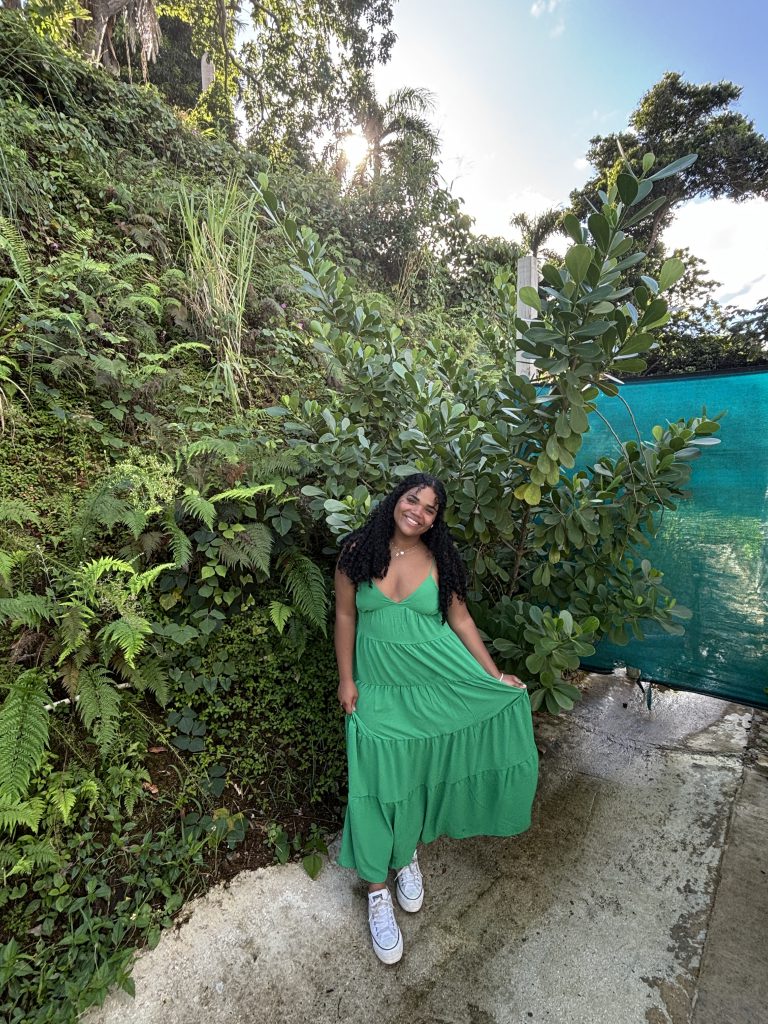 a girl wearing a green dress poses in a tropical setting