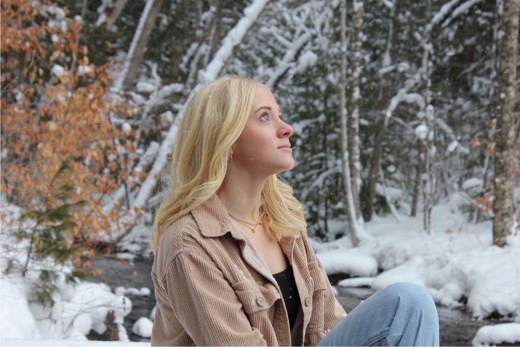 a girl with blonde hair poses outside in a winter setting
