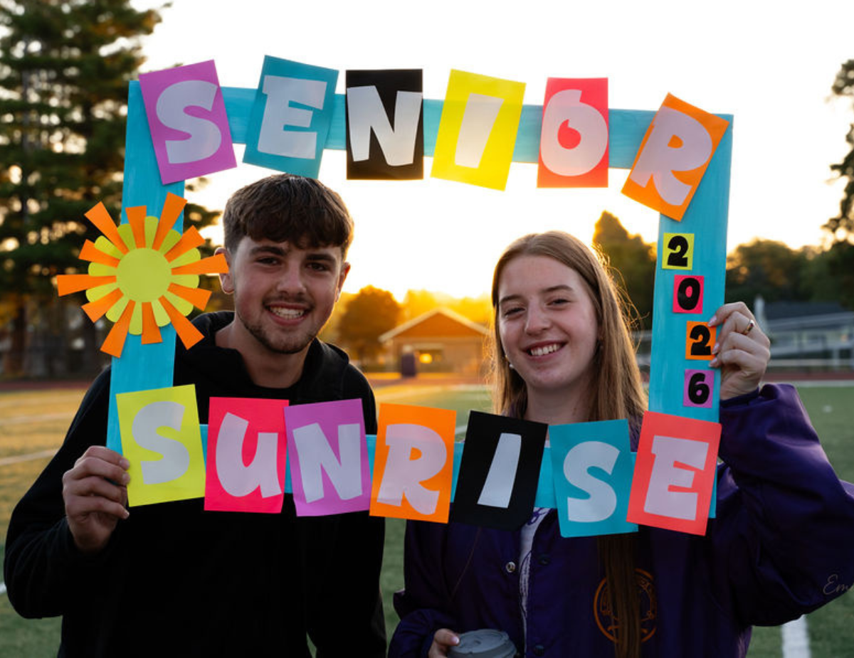 a teen boy and girl pose with a sunrise behind them