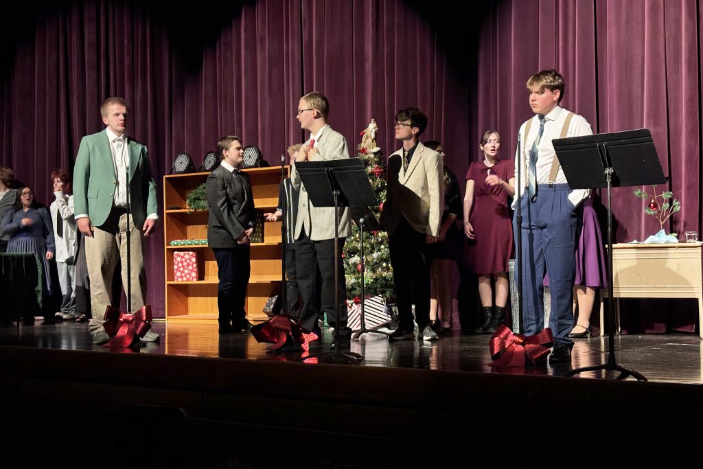 a group of young actors stand on a stage in front of a purple curtain