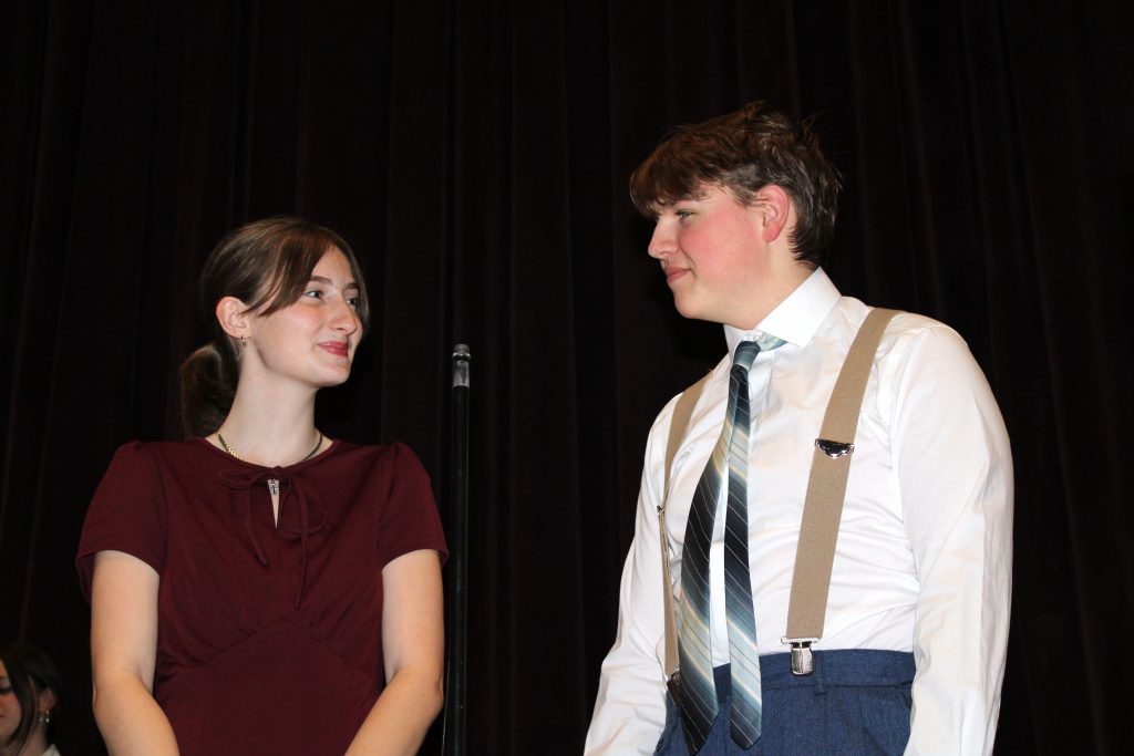 a teenaged girl and boy stand on a theatrical stage