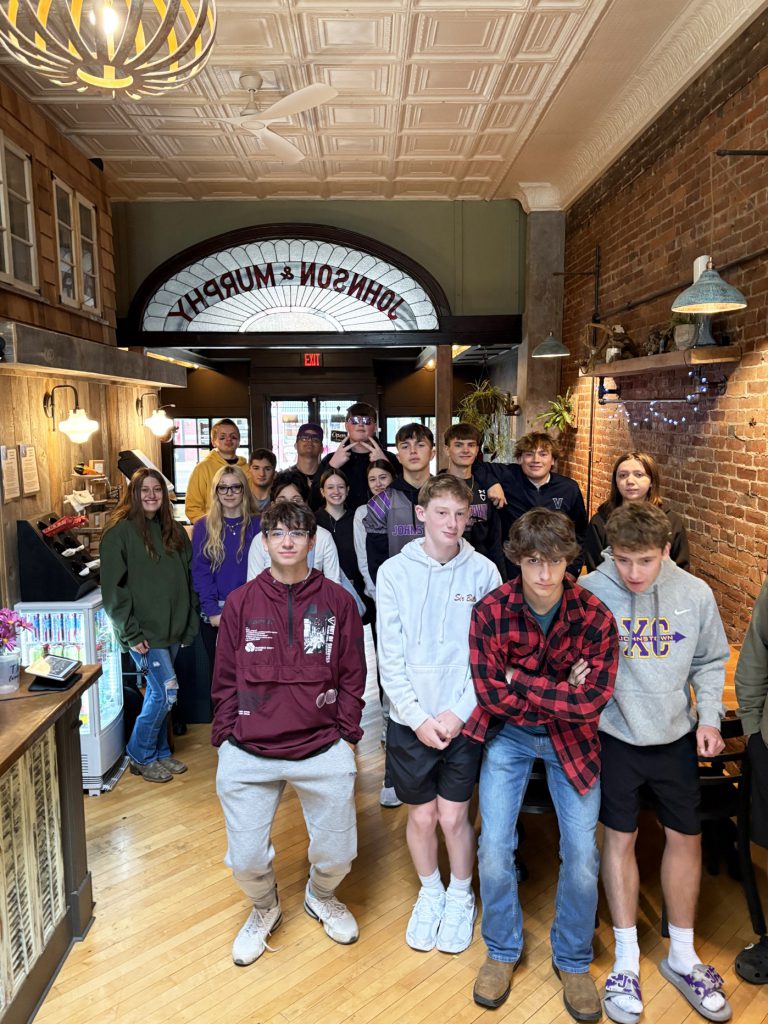 students pose inside a brick building