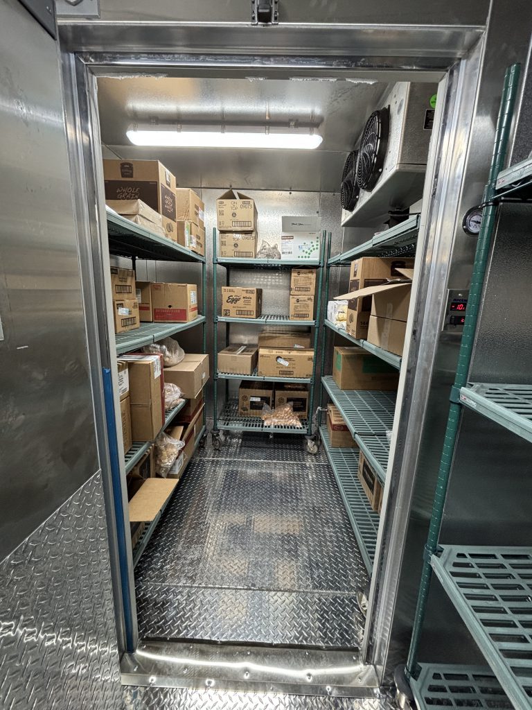 the inside of a cooler with frozen food on a shelf