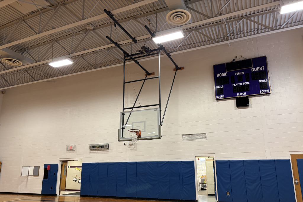 a newly painted gymnasium with a basketball hoop and score board