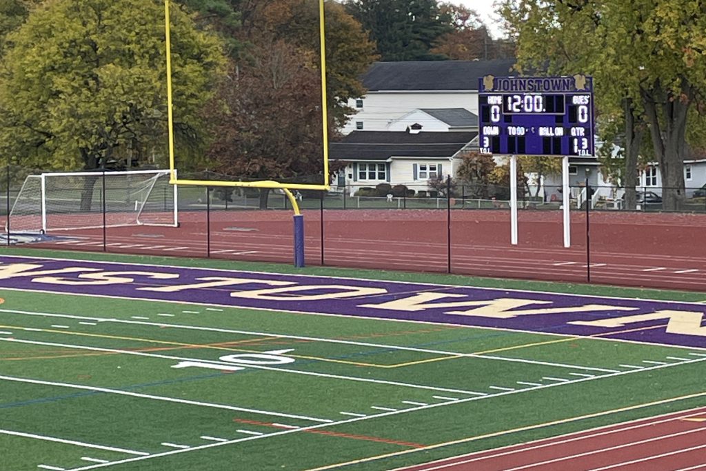 a scoreboard is shown at the end of a turf football field