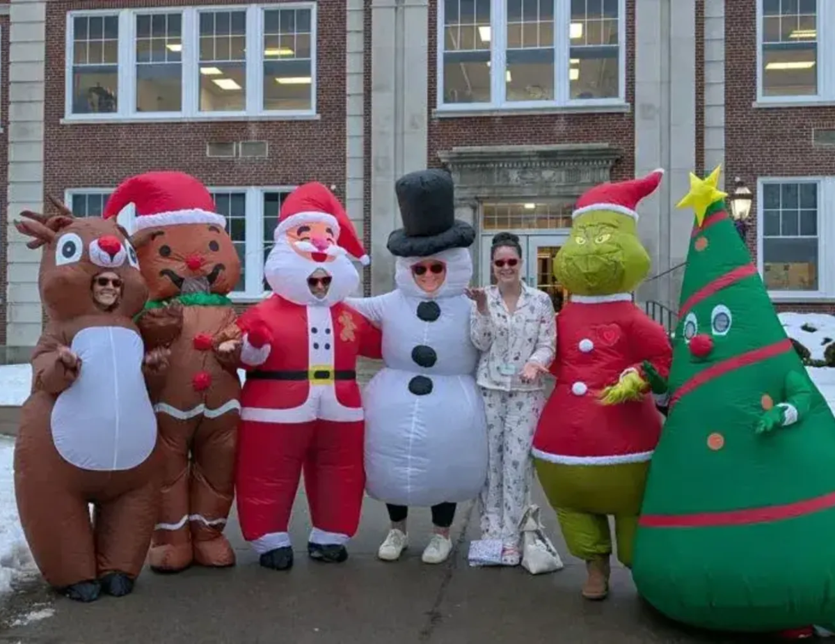 a group of adults are dressed up in inflatable holiday costumes in front of a brick building