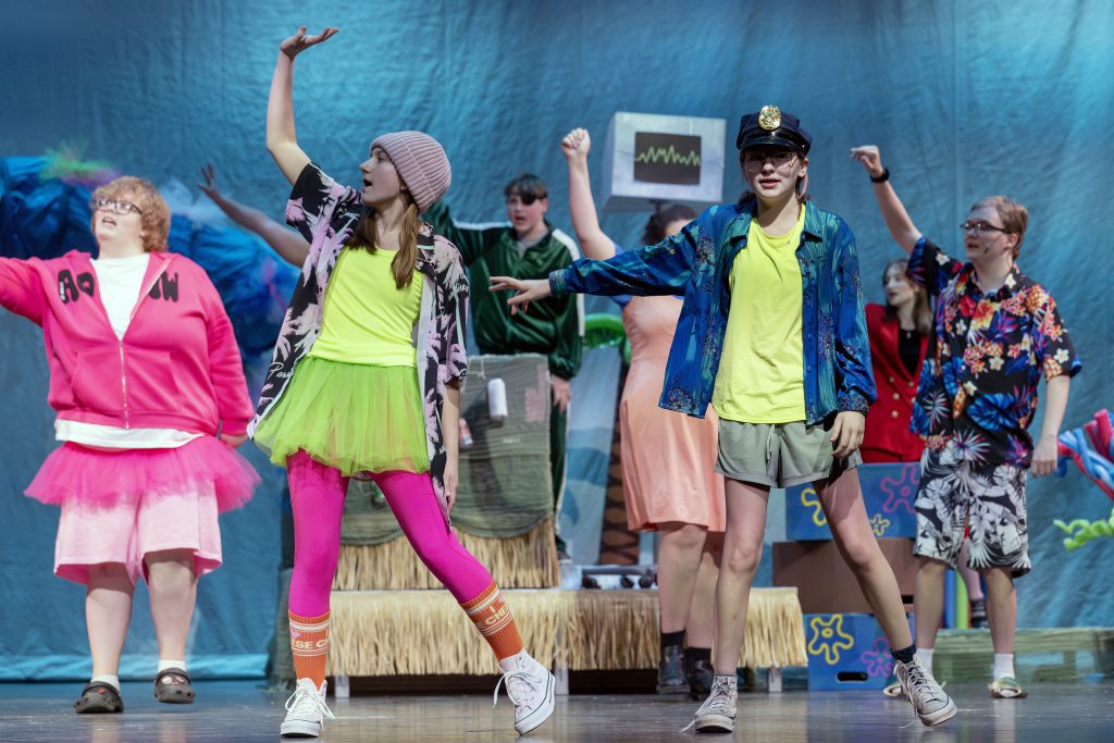 students dance on stage in a theater