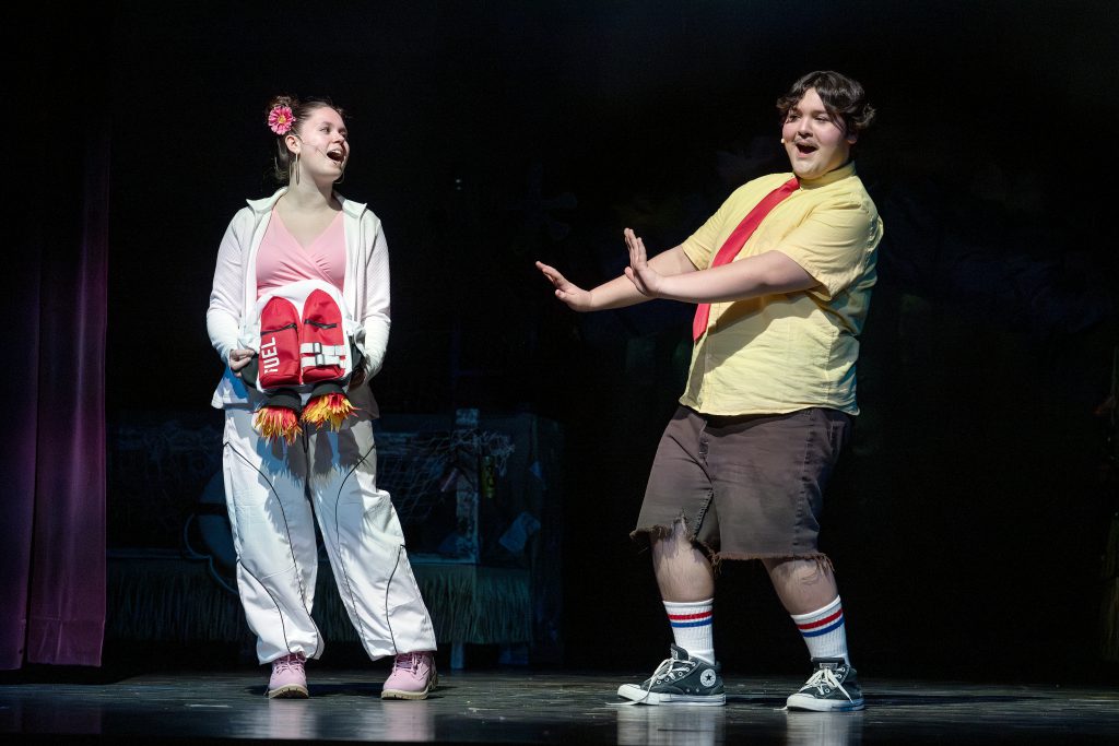 a young teen girl and boy act out a scene on a theatrical stage