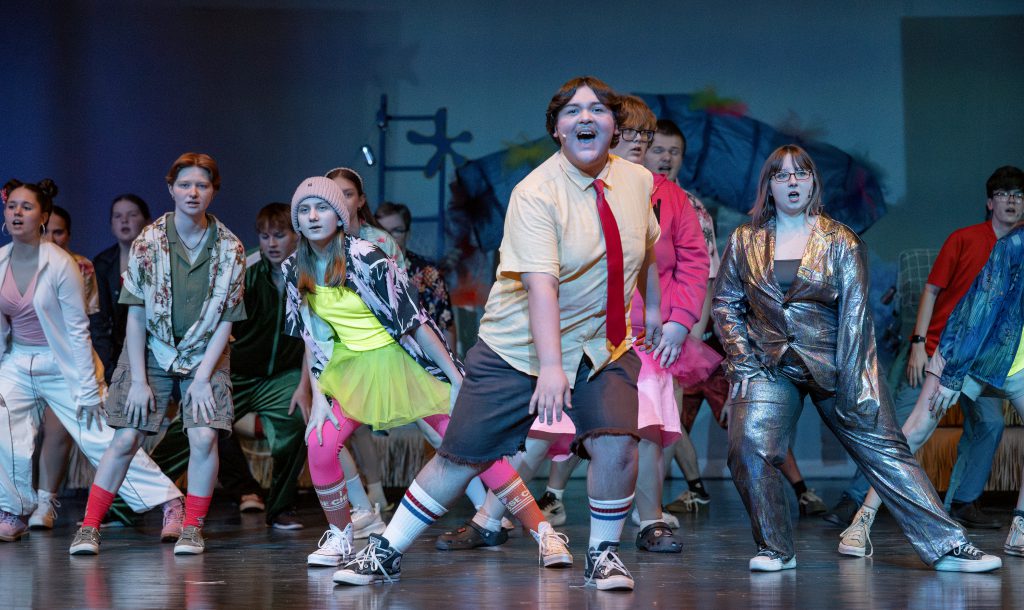 the cast of a musical performs an act on a stage