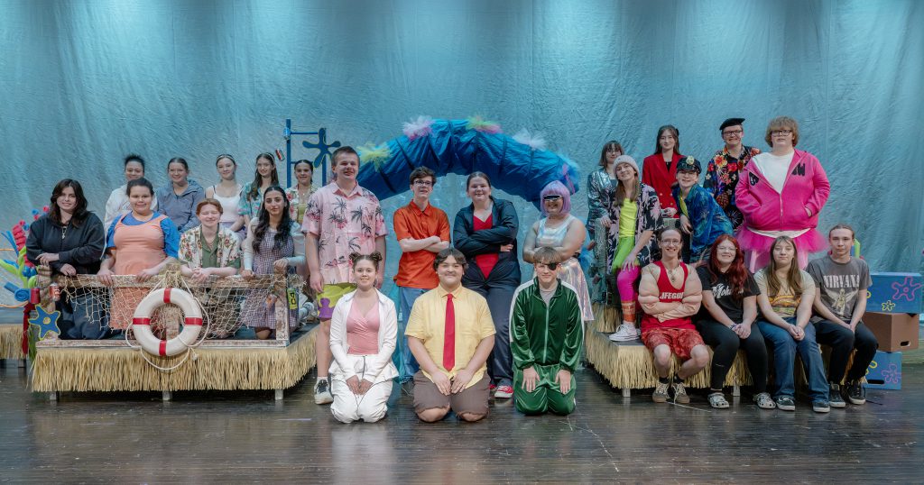 the cast of a play poses on a theatrical stage