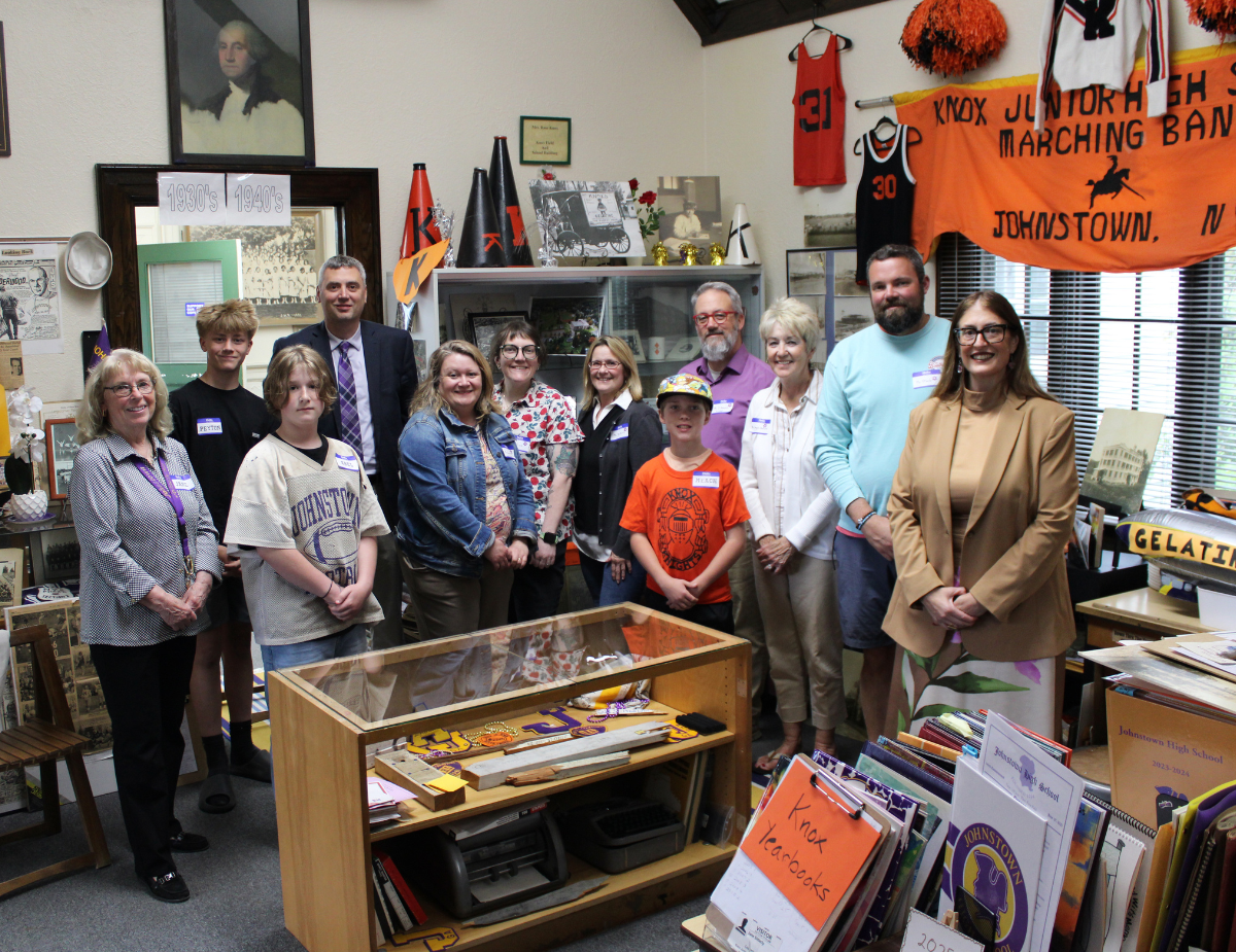a group of adults and students pose inside a museum
